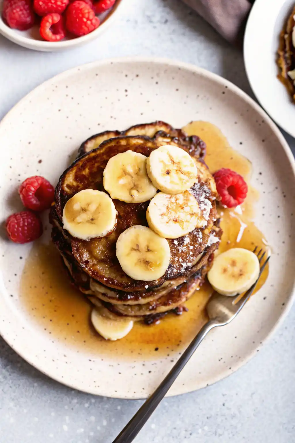 Stack of easy cottage cheese pancakes with no flour topped with banana slices and maple syrup
