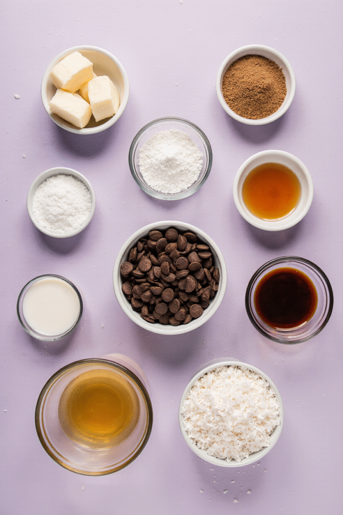 Ingredients for coconut caramel chocolate chip cookies including butter, coconut sugar, eggs, vanilla, flour, baking soda, salt, chocolate chips, caramel, shredded coconut, and coconut milk arranged in bowls