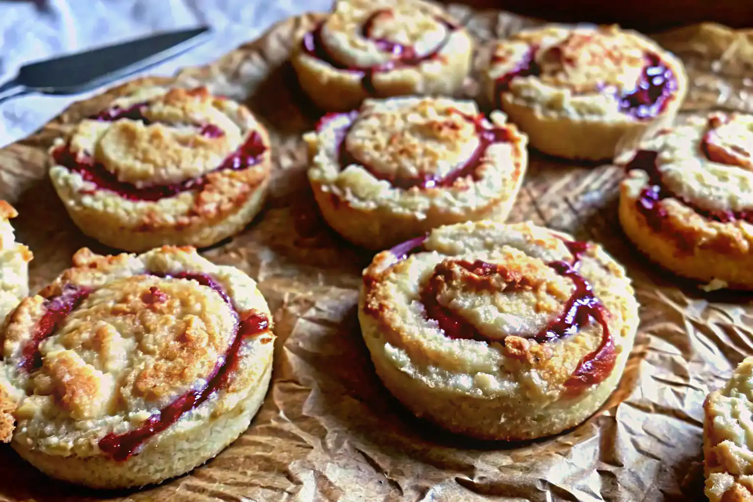 Close-up of golden strawberry almond flour cookies with jam swirls on parchment paper