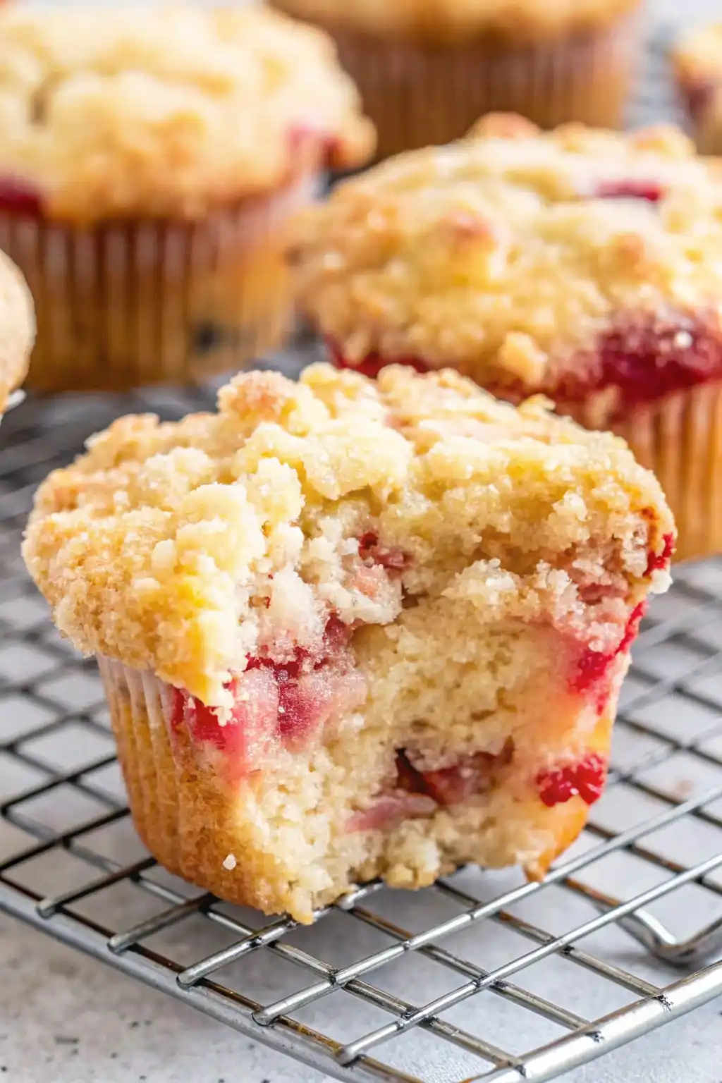 Freshly baked white chocolate strawberry muffin with crumb topping on a cooling rack