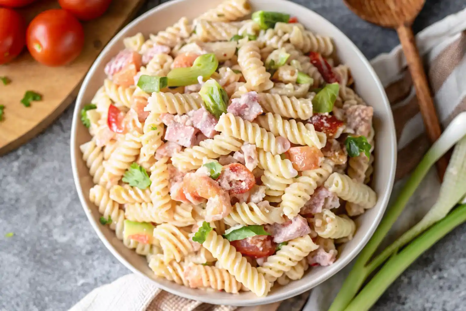 Creamy pasta salad with cottage cheese in a bowl with tomatoes and fresh herbs.